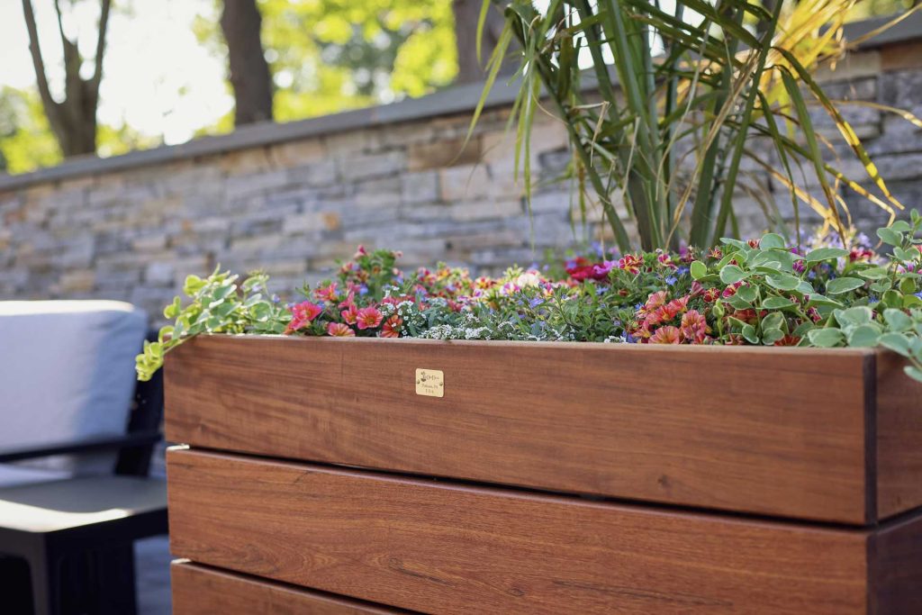 wooden square planter with various colored flowers blooming from it